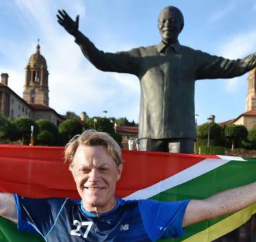 British comedian Eddie Izzard holds a South African flag beneath a statue of former president Nelson Mandela at the government’s Union Buildings in Pretoria, South Africa, Sunday, March 20, 2016. (AP Photo)